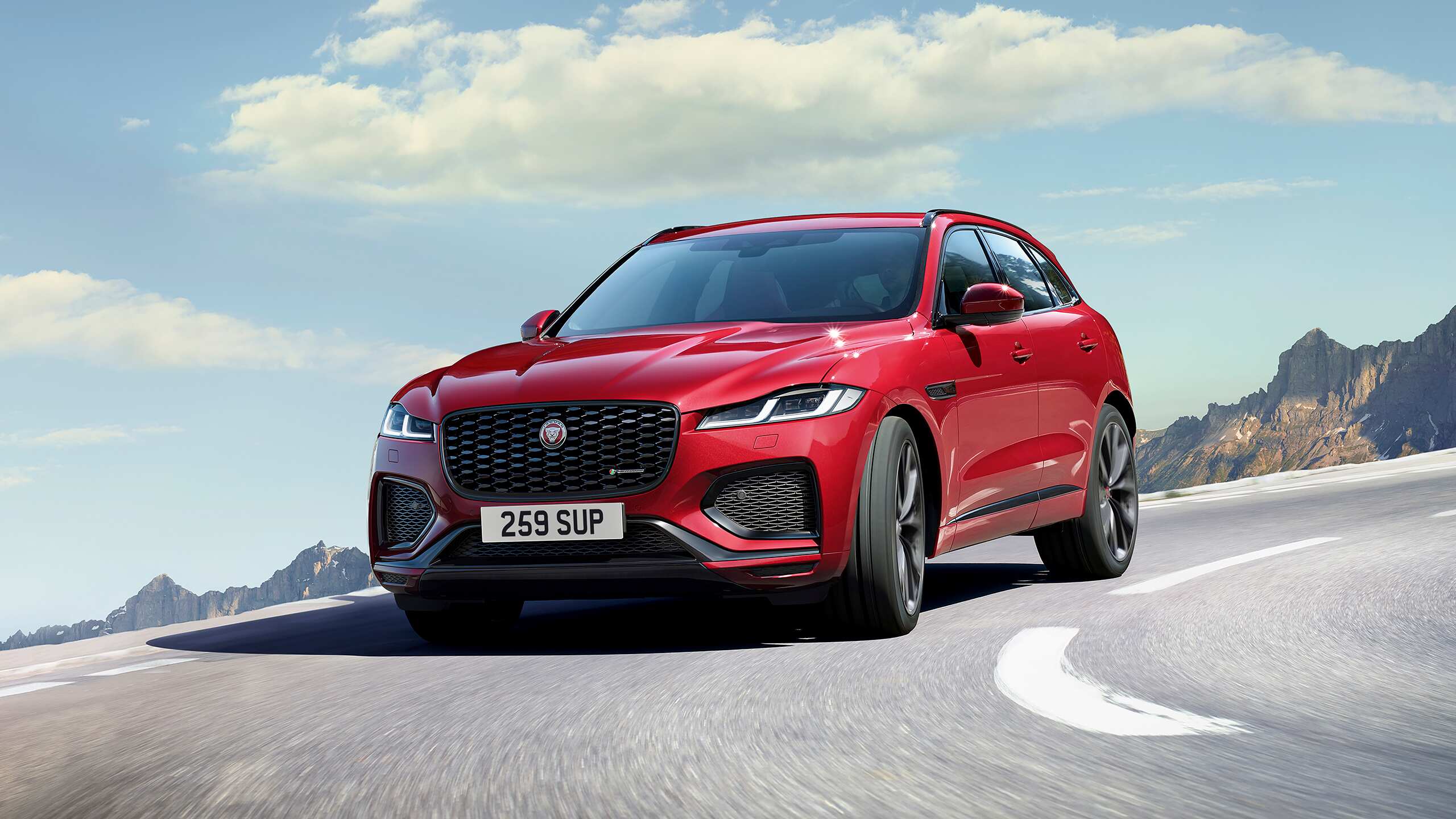 New Jaguar car moving on hill road with cloudy background