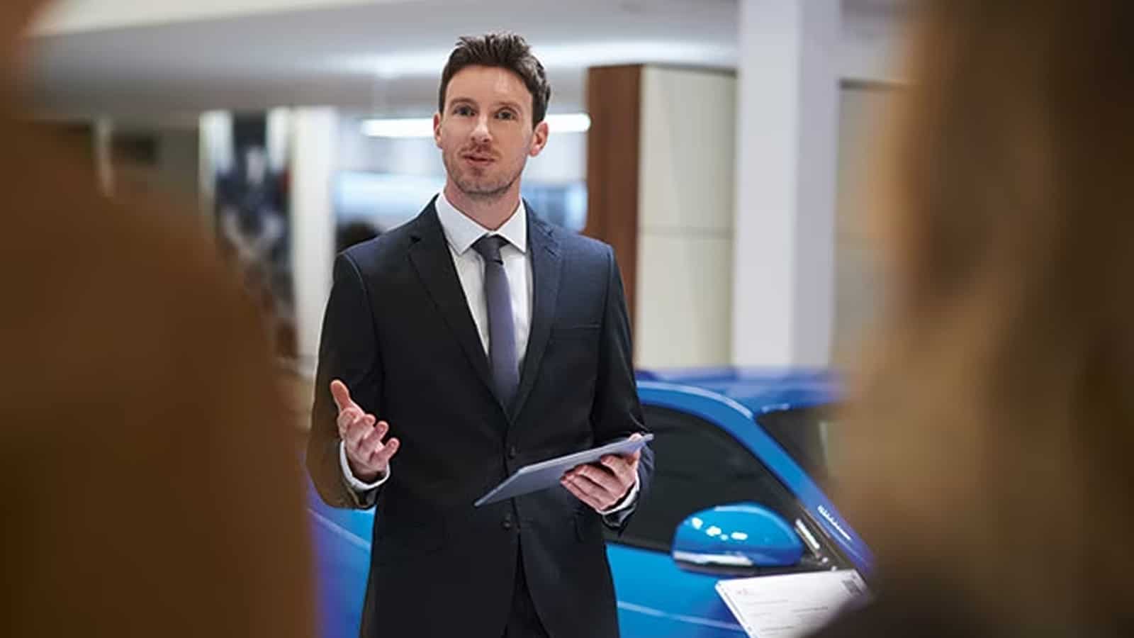 Male professional marketer explaining about car details at retailer outlet