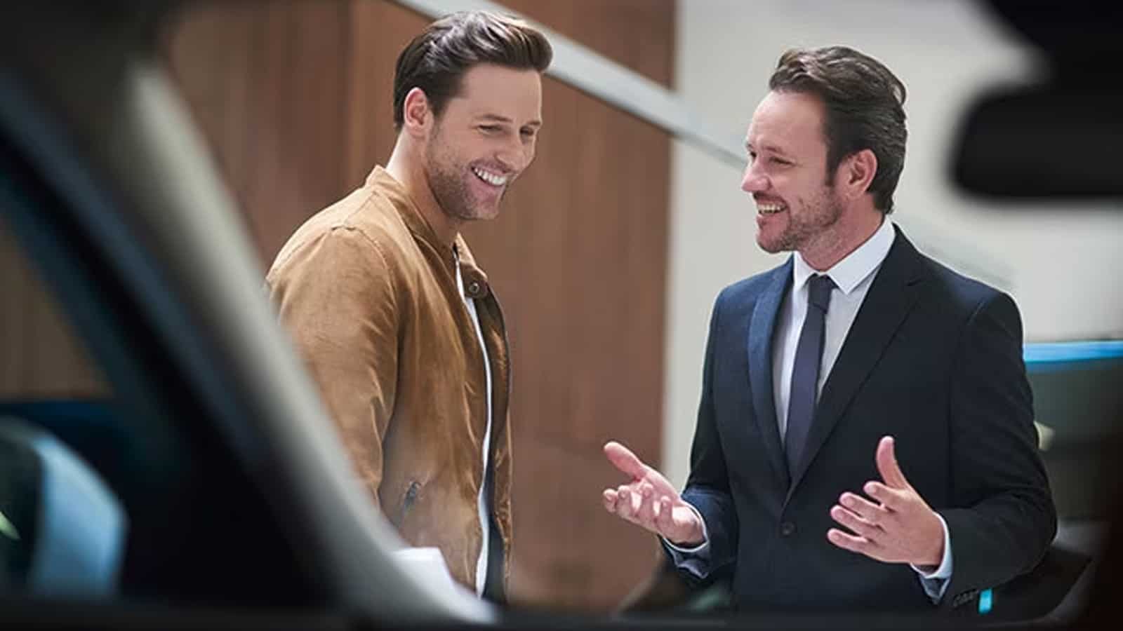 Male professional marketer explaining about car details at retailer outlet